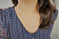 A women wearing a sterling silver and gold vermeil champagne pearl necklace with a potato-shaped pearl drop and a gold heart-shaped clasp.