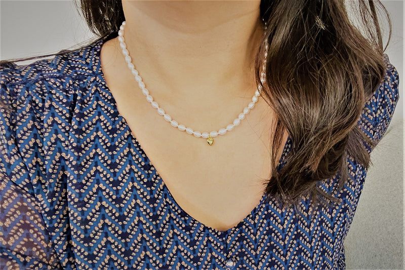 A women wearing a sterling silver and gold vermeil champagne pearl necklace with a potato-shaped pearl drop and a gold heart-shaped clasp.