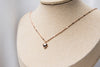 A rose gold chain necklace with a small heart penant