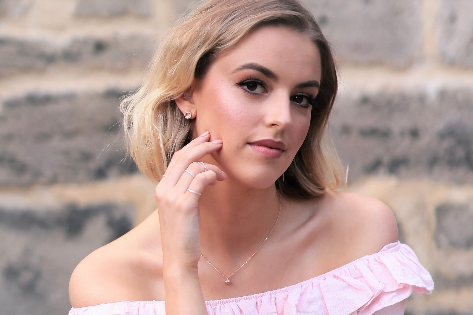 A rose gold chain necklace with a small heart penant worn by a woman