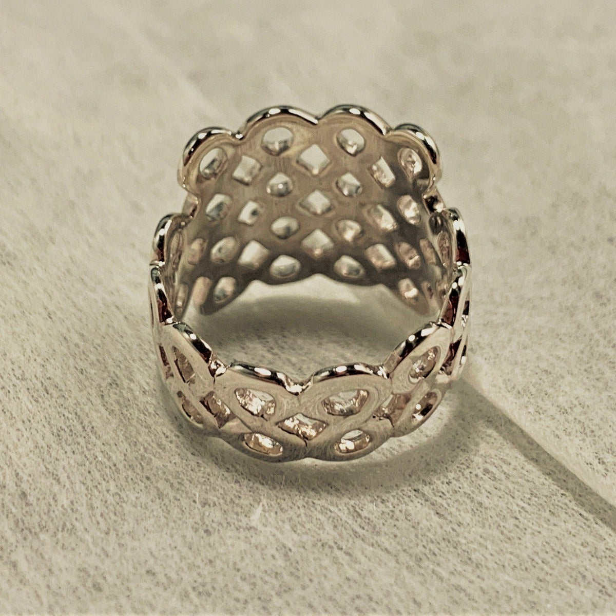 A honeycomb shaped ring on a white fabric background