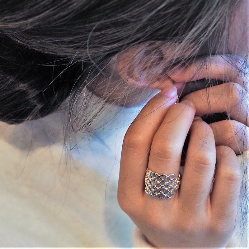  close up of a woman wearing a honeycomb design ring.