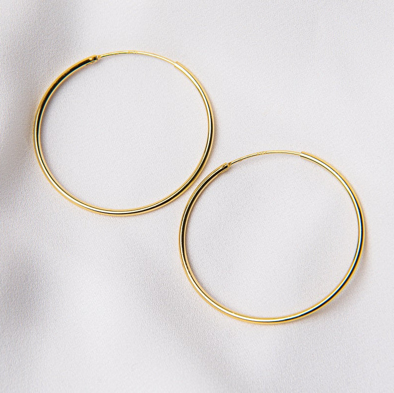 Two hoop earrings made of sterling silver with gold vermeil coating, displayed on a white background.