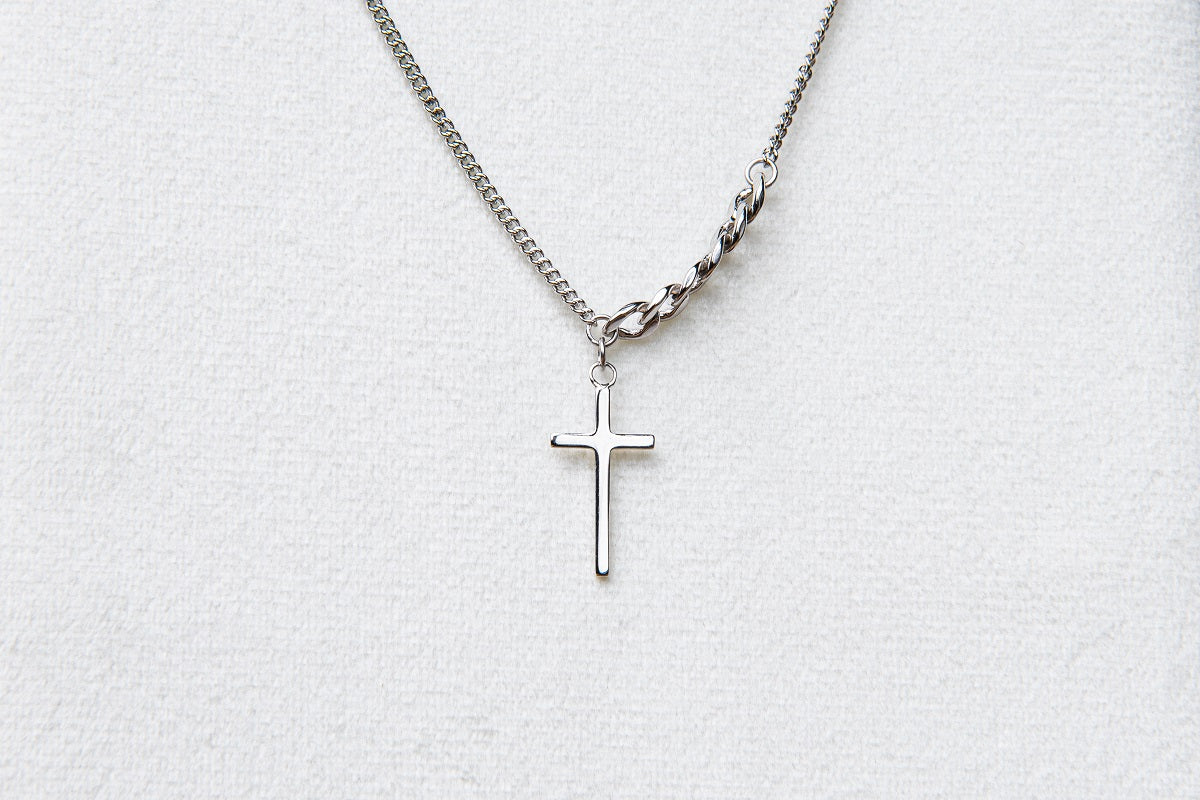 A silver necklace with a small cross pendant centered on a white background.