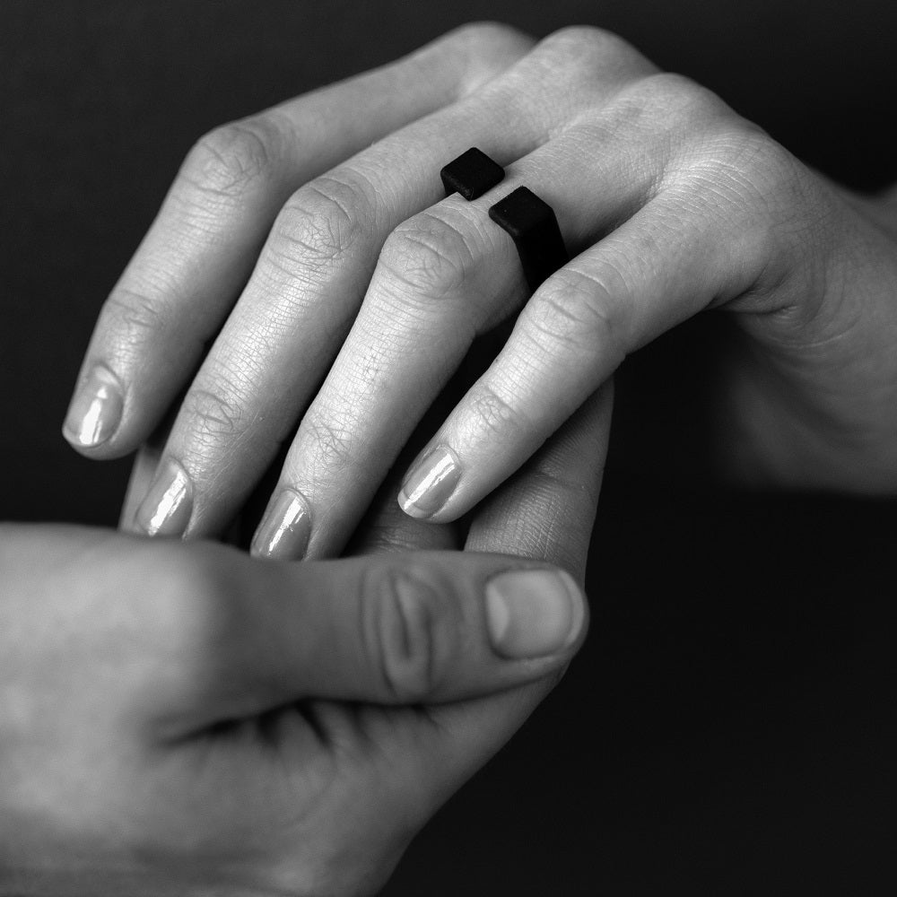 Black and white close up picture of a hand wearing a black ring