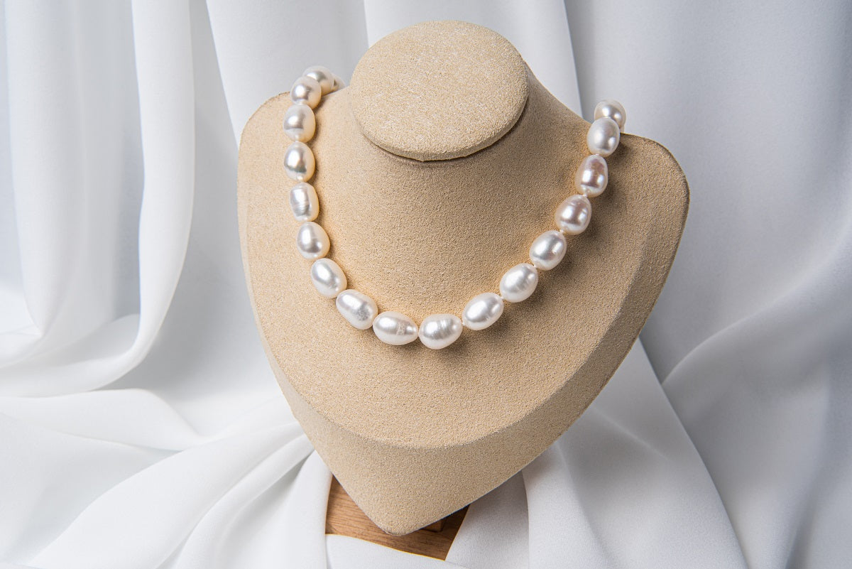 A necklace of fresh water pearls displayed on a necklace stand.