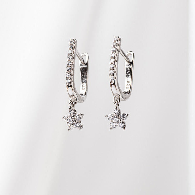 A pair of silver hoop earrings with dangle of diamond cubic zirconia, placed on a white background.