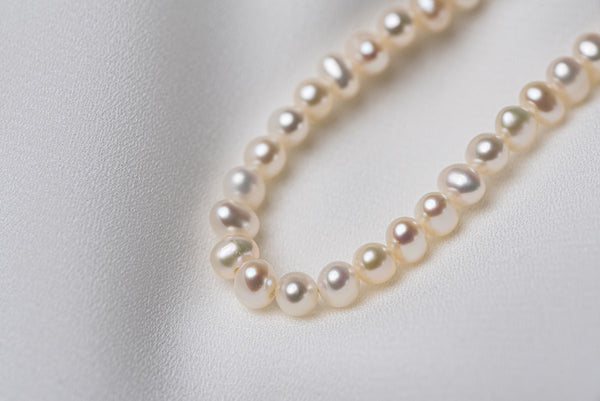 A sterling silver freshwater white pearl necklace on a white background.