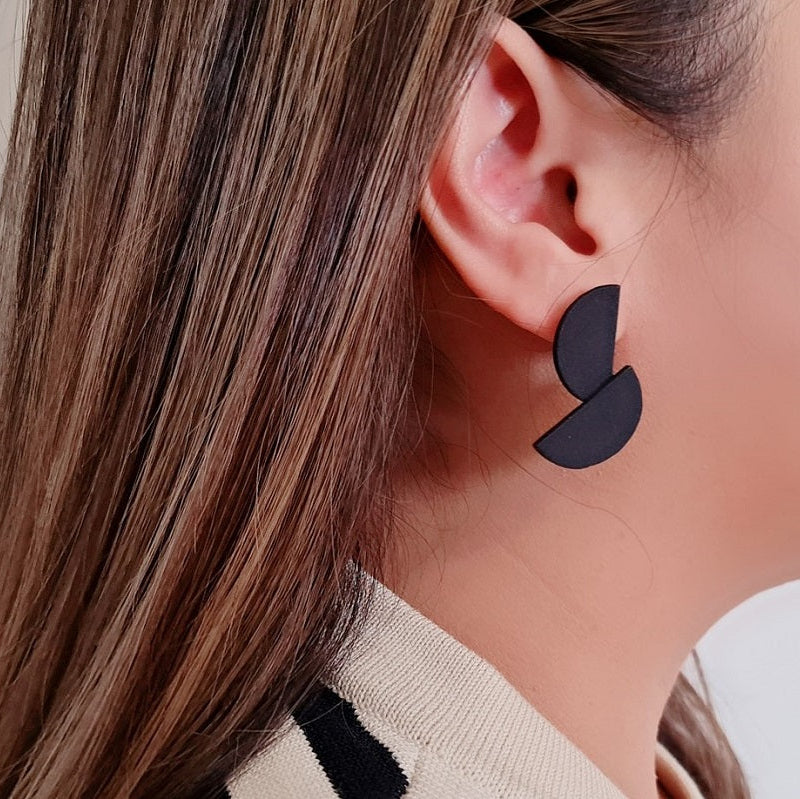 Close up of a woman wearing matt black minimalist design earrings