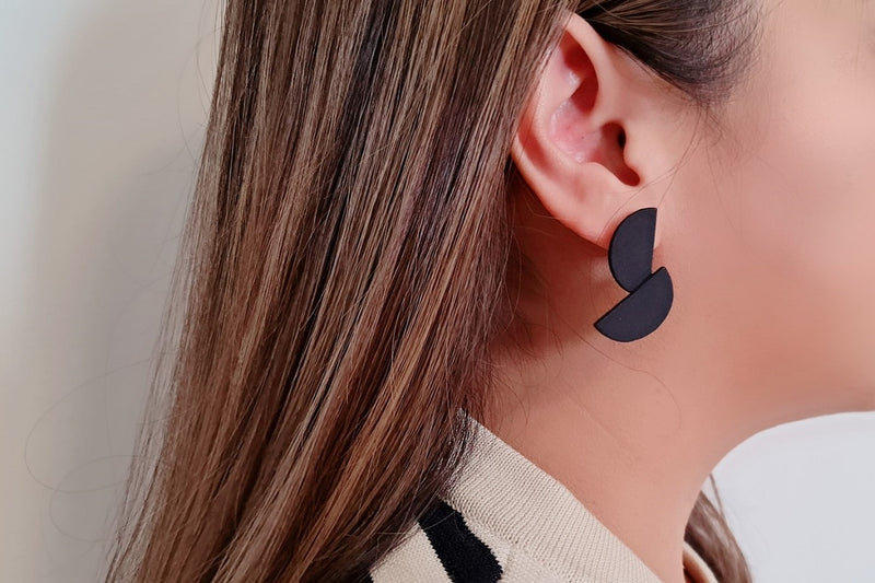 Close up of a woman wearing matt black minimalist design earrings