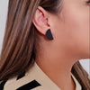 Close up of a woman wearing matt black minimalist design earrings