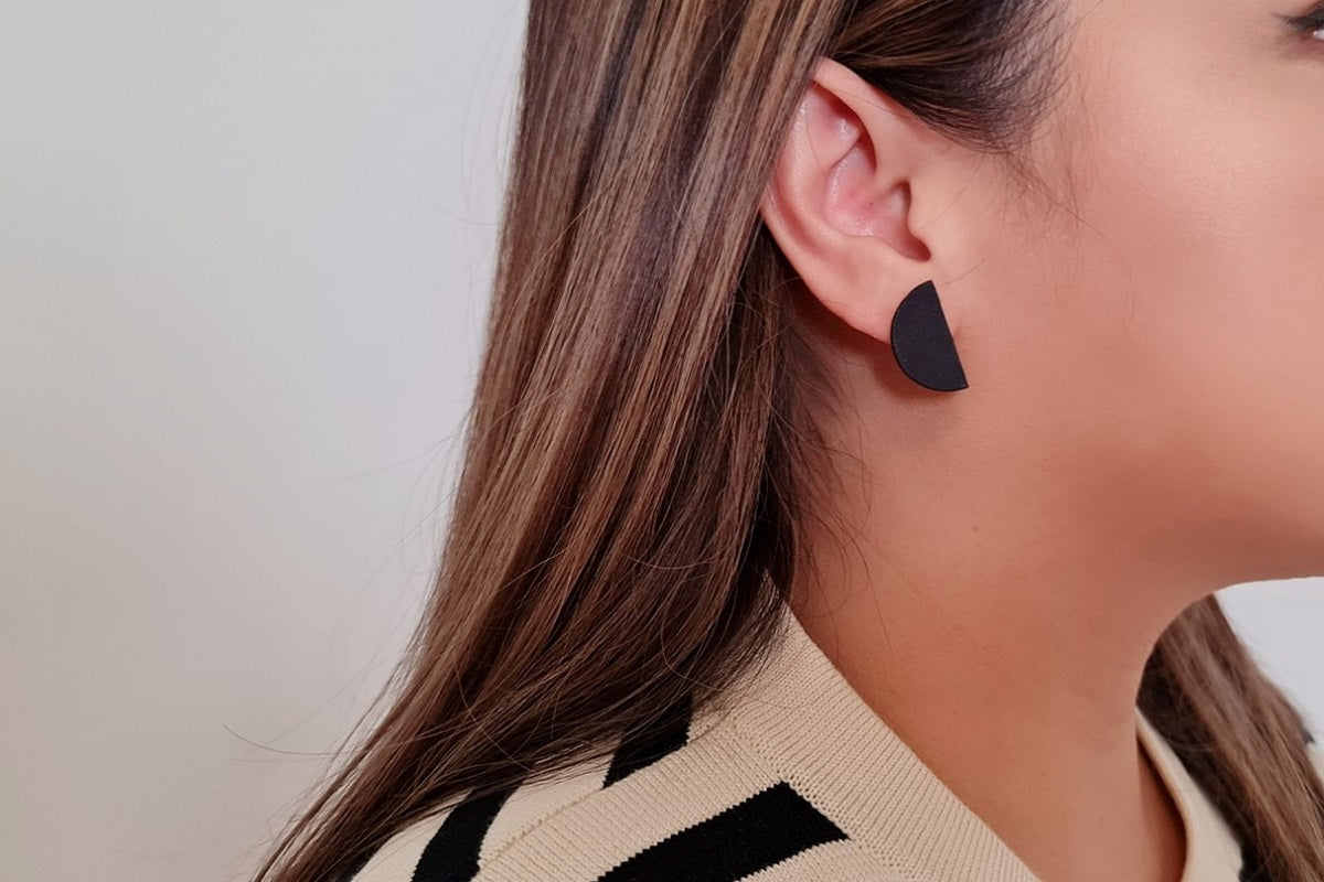 Close up of a woman wearing matt black minimalist design earrings