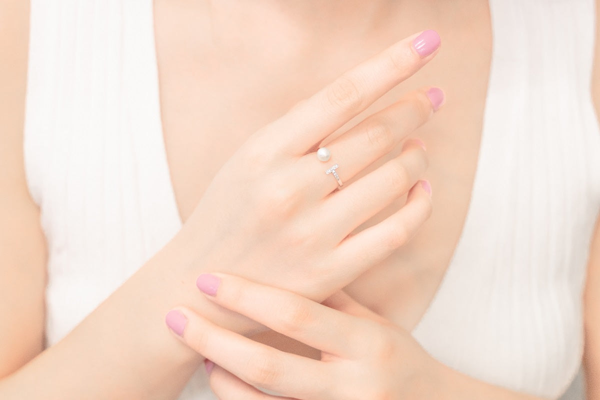 Close up of a womans hand wearing a silver ring featuring a pearl and cubic zirconias