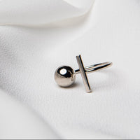 A close up of a sterling silver ring featuring a bar abd a ballk on a white fabric background