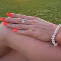A close up of a womans hand wearing a silver ring in the shape of a wave
