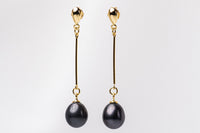 A pair of black pearl earrings with gold dangle components and butterfly backs, displayed against a white background.