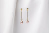 A pair of pearl earrings with gold vermeil  clasps and butterfly backs, displayed against a white fabric background.