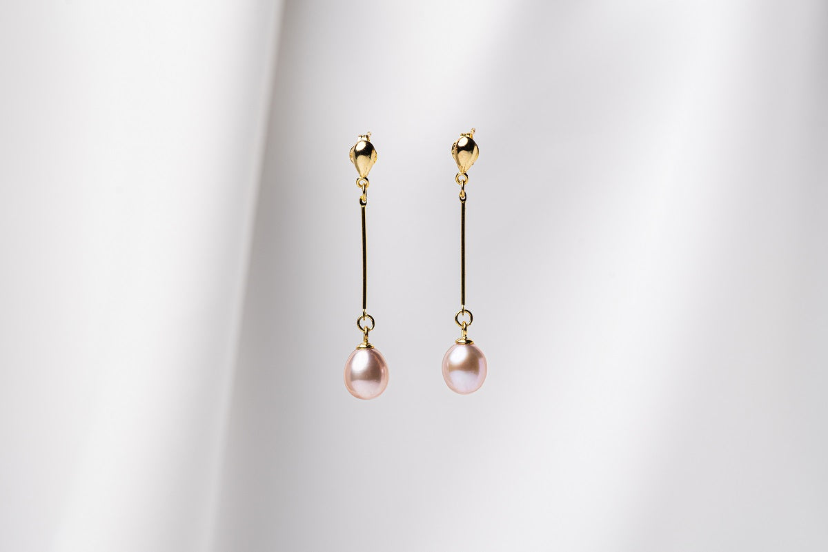 A pair of pearl earrings with gold vermeil  clasps and butterfly backs, displayed against a white fabric background.