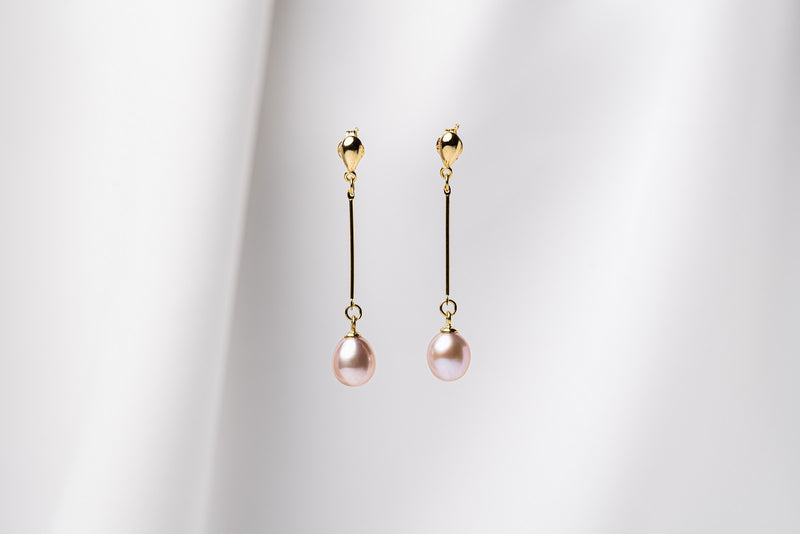 A pair of pearl earrings with gold vermeil  clasps and butterfly backs, displayed against a white fabric background.