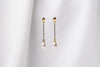 A pair of pearl earrings with a gold vermeil dangle design and butterfly backs, displayed against a white fabric backdrop.