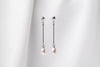 A pair of pearl earrings with a silver dangle design and butterfly backs, displayed against a white fabric backdrop.