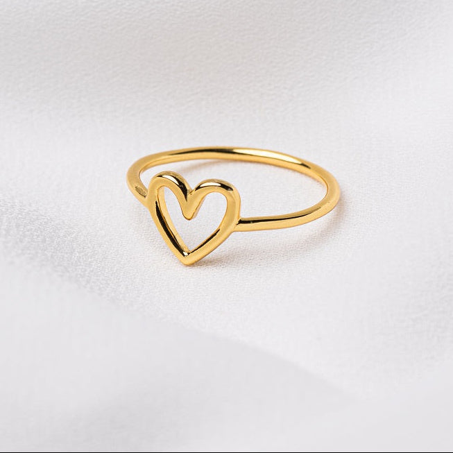A polished gold vermeil ring with an open heart design, displayed on a white surface.