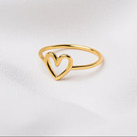 A polished gold vermeil ring with an open heart design, displayed on a white surface.