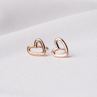 A pair of heart-shaped stud earrings made of sterling silver with rose gold vermeil coating, displayed on a white background.
