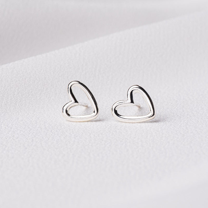A pair of heart-shaped stud earrings made of sterling silver displayed on a white background.