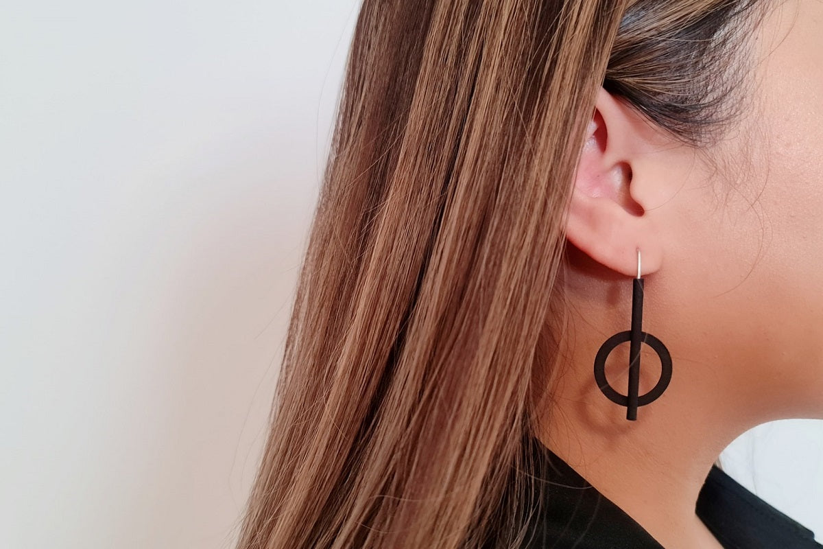 Close up of a woman wearing a matt black earring with a white background
