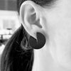 Black and white close up of a woman wearing a matt black pacman shaped earring