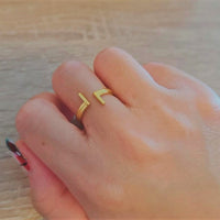 A close up of a hand wearing a gold ring with a paralel design.