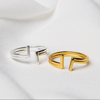 Two rings, one with a silver finish and the other with a gold finish, placed on a white textile surface.