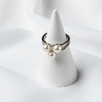 Silver ring featuring three white pearls on a white ring display.