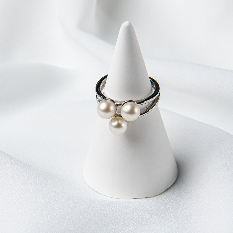 Silver ring featuring three white pearls on a white ring display.