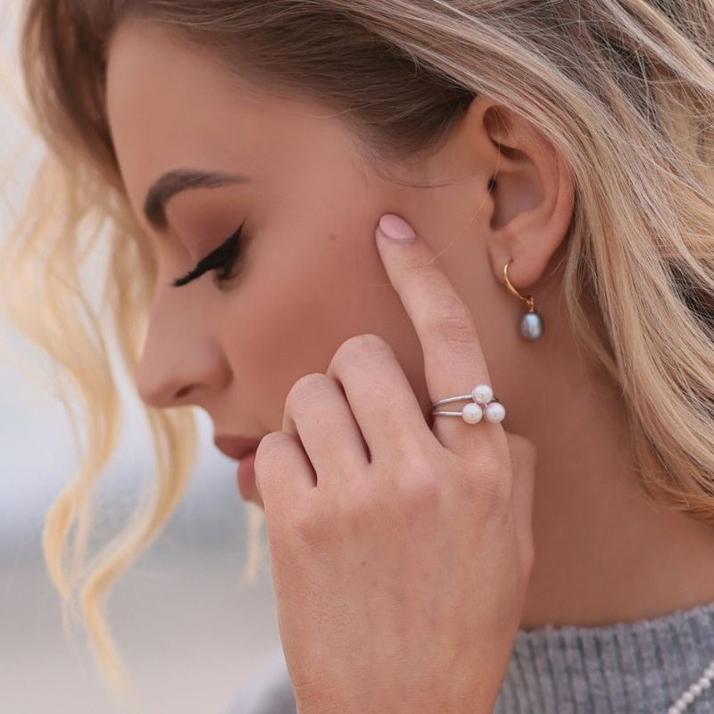A model wearing a silver ring with three white pearls