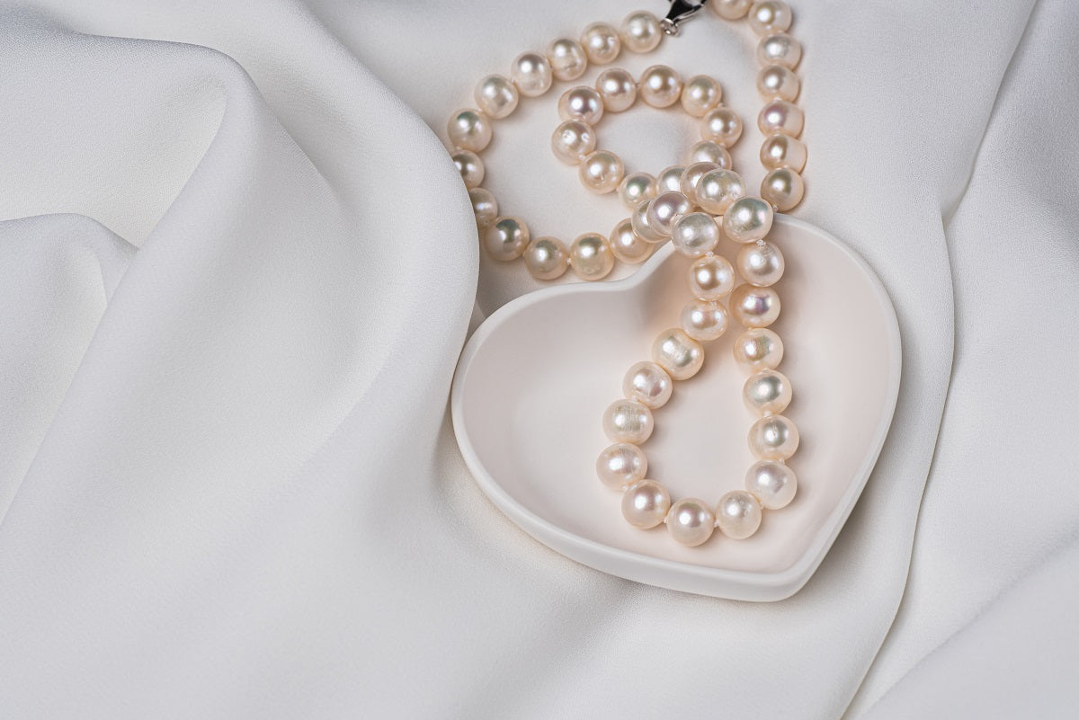A sterling silver freshwater white pearl necklace displayed  on a heart shaped display small tray.