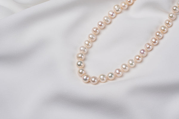 A sterling silver freshwater white pearl necklace displayed  on a white fabric.