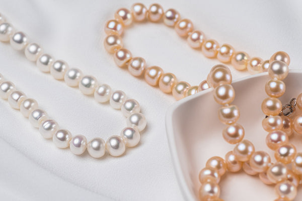 A freshwater white and champagne pearl necklace display on a white background 