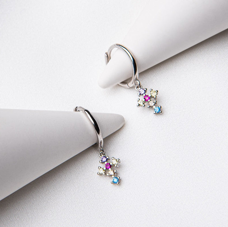 A pair of sterling silver hoop cross earrings with a multicolored dangle design, displayed on a white textured surface.