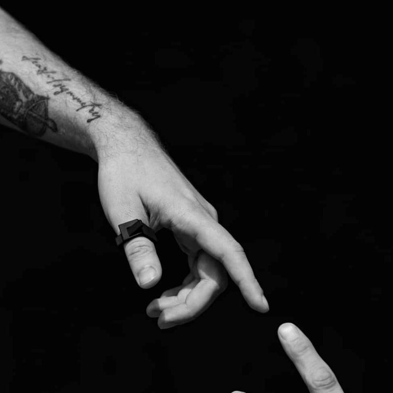 Black and white close up of a hand wearing a matt black ring