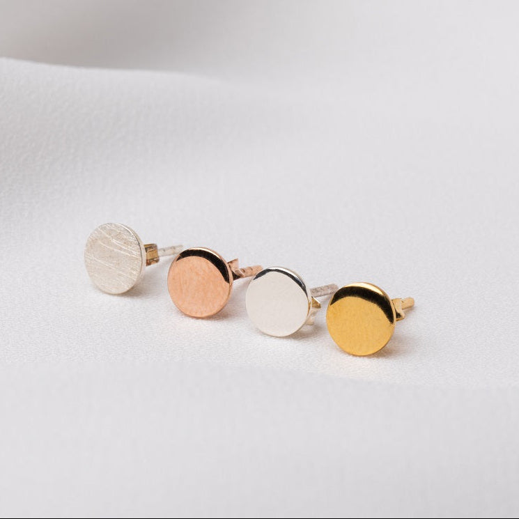 Four round studs on a white cloth background