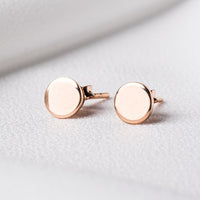 Pair of rose gold round studs on a white cloth background