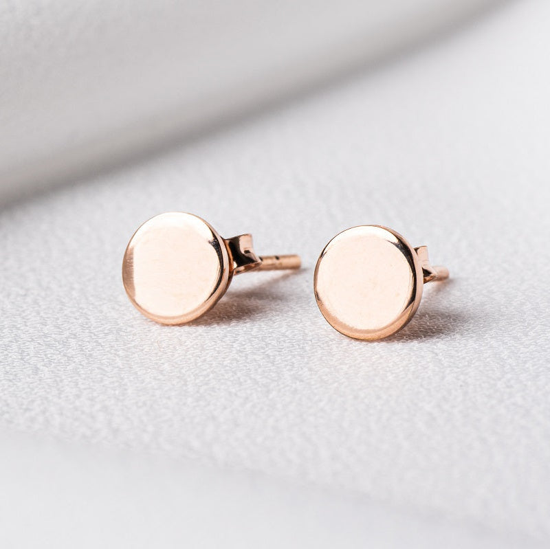 Pair of rose gold round studs on a white cloth background