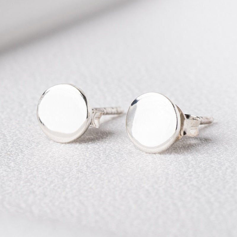 Pair of sterling silver round studs on a white cloth background