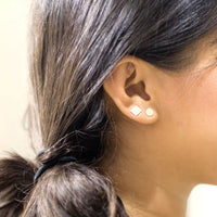 Close up of a model wearing Sterling silver studs, one square and one round.