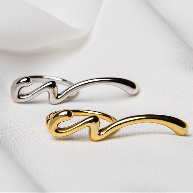 Two rings, one with a silver finish and another with a gold finish, positioned on a white fabric surface.