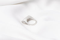 A polished silver ring with a unique design, featuring a loop-shaped top on a white background.