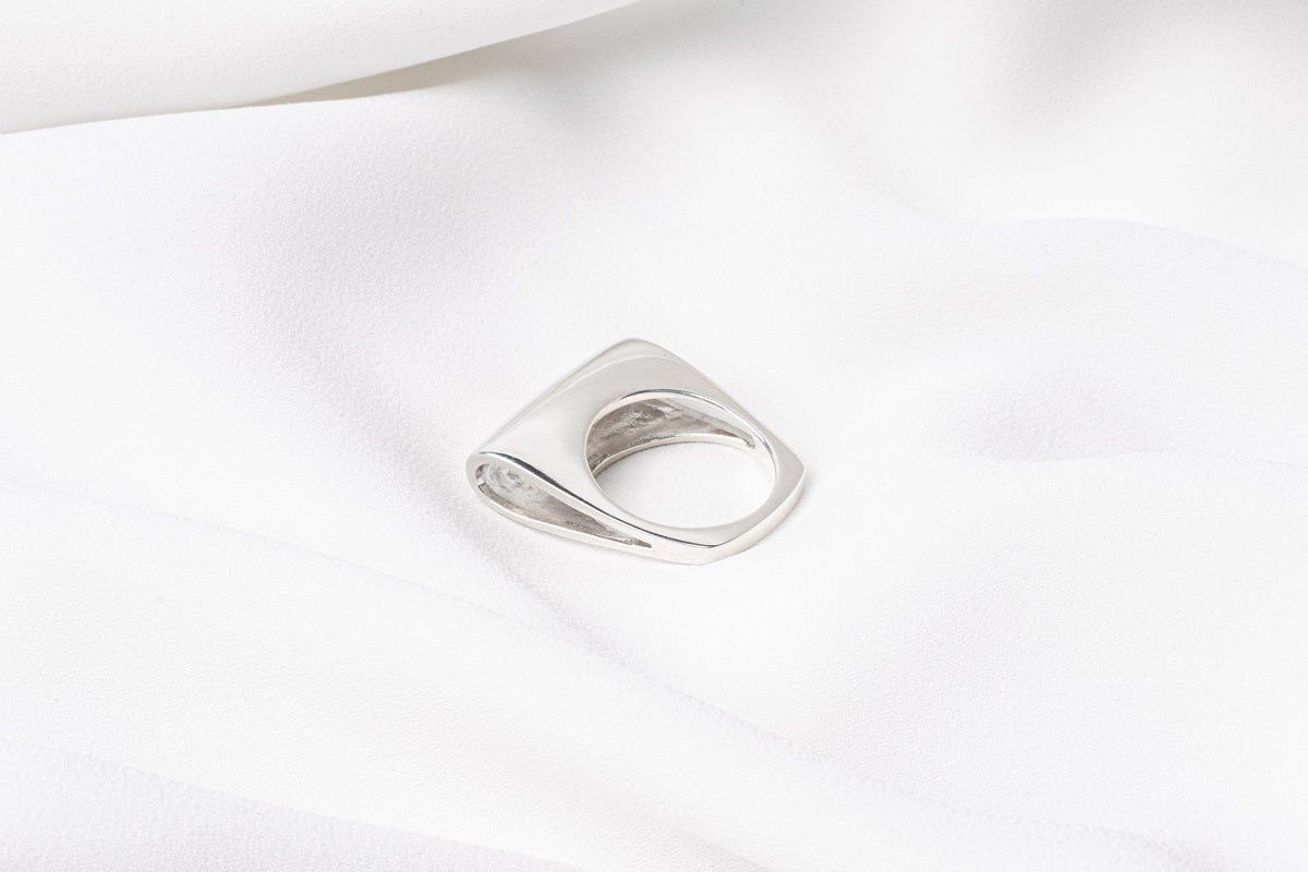 A polished silver ring with a unique design, featuring a loop-shaped top on a white background.