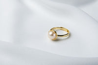 A gold pearl ring on a white cloth background